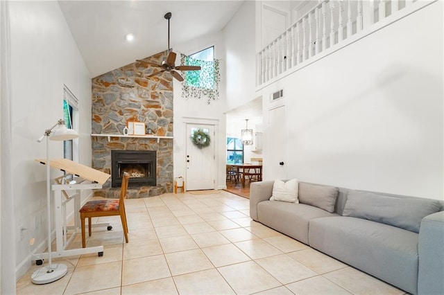 living room featuring a stone fireplace, ceiling fan, high vaulted ceiling, and light tile patterned flooring