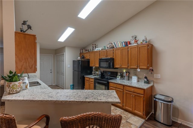 629 Spring Lake Dr W, Mobile, AL 36695 - kitchen with black appliances, vaulted ceiling, a peninsula, brown cabinets, and light stone counters