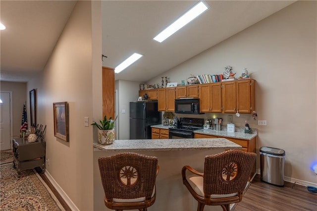 629 Spring Lake Dr W, Mobile, AL 36695 - kitchen featuring black appliances, vaulted ceiling, dark wood-style floors, a peninsula, and brown cabinetry