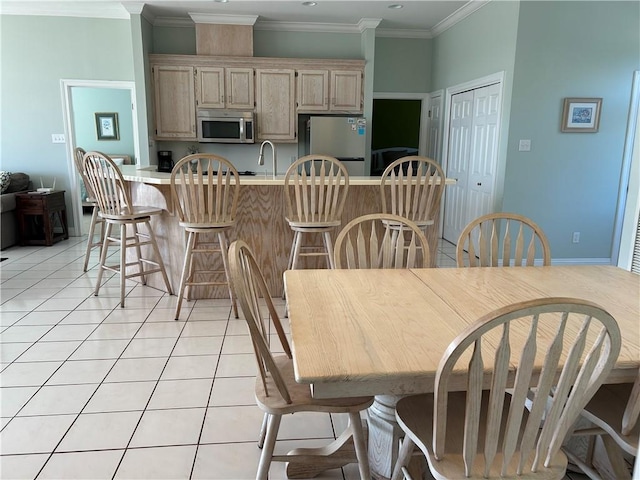 dining room featuring sink, light tile patterned floors, and crown molding