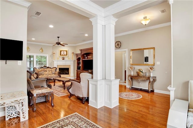 living room with ornate columns, ornamental molding, wood-type flooring, and ceiling fan