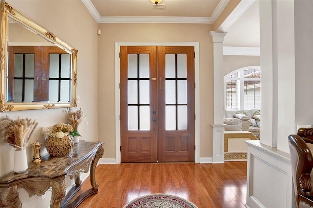 entryway with french doors, ornamental molding, decorative columns, and light wood-type flooring