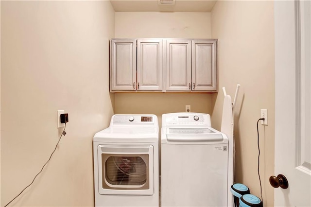 clothes washing area with cabinets and washing machine and dryer