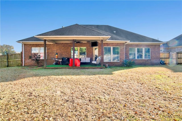 back of property with a yard and ceiling fan