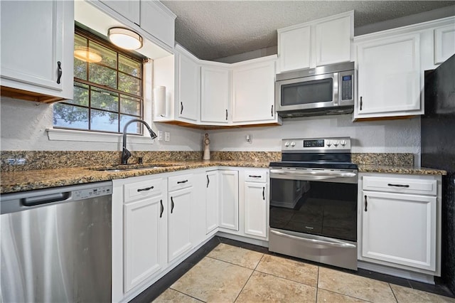 8500 Cindy Lou Dr, Theodore, AL 36582 - kitchen featuring appliances with stainless steel finishes, white cabinets, tile patterned floors, a textured ceiling, and dark stone counters