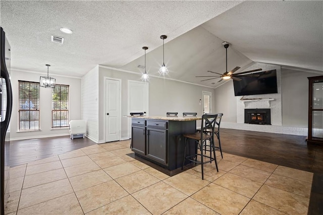 8500 Cindy Lou Dr, Theodore, AL 36582 - kitchen with a textured ceiling, vaulted ceiling, a ceiling fan, a fireplace, and a kitchen bar
