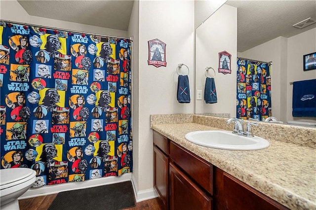 bathroom featuring wood-type flooring, vanity, toilet, and a textured ceiling