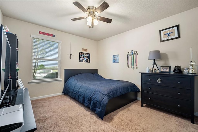 bedroom with ceiling fan, light colored carpet, and a textured ceiling