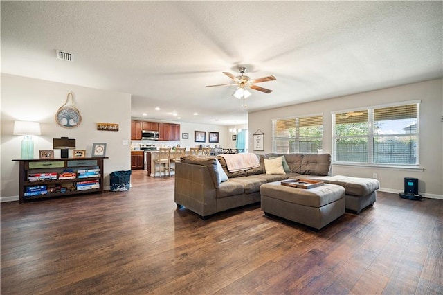 living room featuring dark hardwood / wood-style floors, a textured ceiling, and ceiling fan