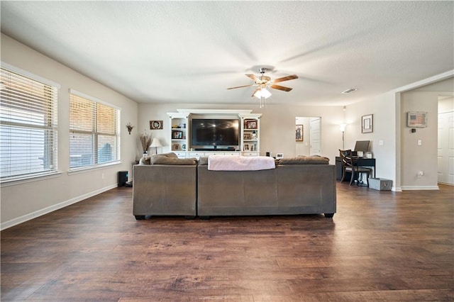 living room featuring ceiling fan, a textured ceiling, and dark hardwood / wood-style floors