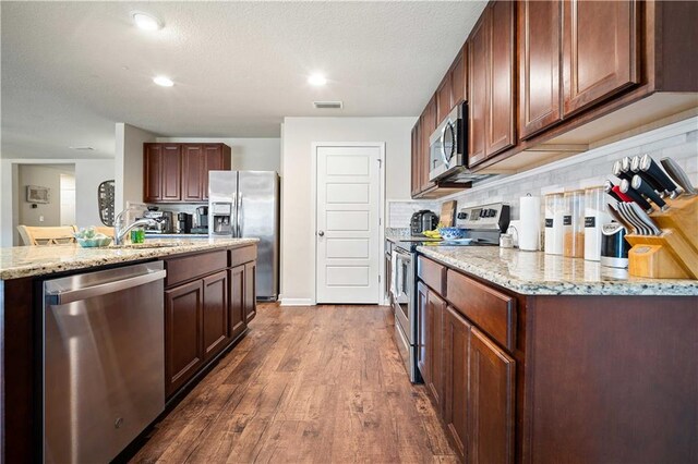 kitchen featuring backsplash, sink, light stone counters, stainless steel appliances, and dark hardwood / wood-style floors