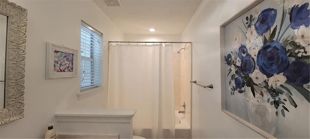 bathroom with a textured ceiling and shower / bath combo