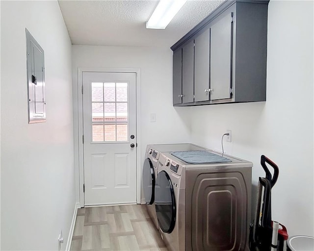 washroom with cabinets, washing machine and dryer, electric panel, a textured ceiling, and light hardwood / wood-style flooring