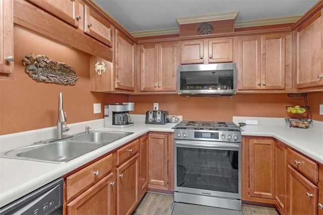 kitchen featuring brown cabinets, appliances with stainless steel finishes, light countertops, and a sink