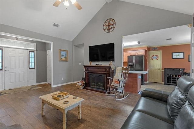 living area featuring high vaulted ceiling, a fireplace, visible vents, and wood finished floors