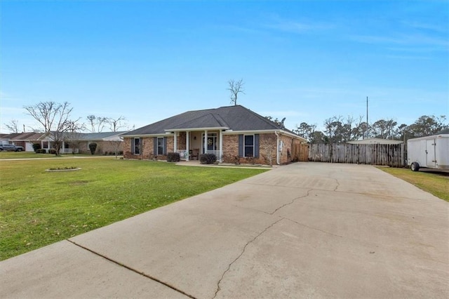 view of front facade with a front yard, concrete driveway, brick siding, and fence