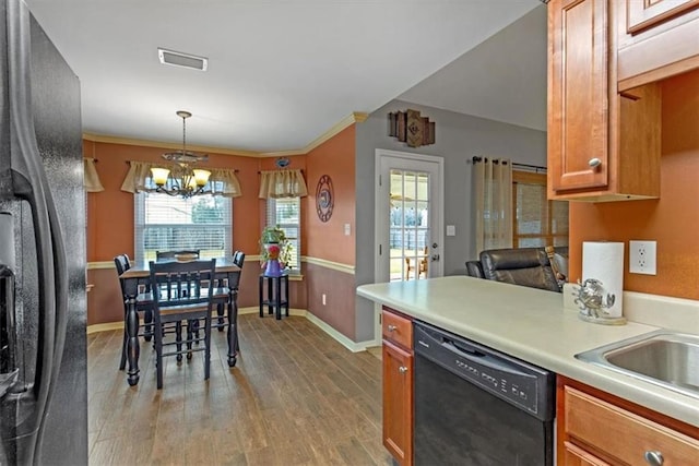 kitchen featuring brown cabinetry, light countertops, light wood-style floors, and black appliances