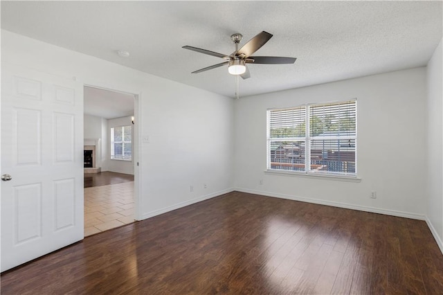 unfurnished room with dark hardwood / wood-style flooring, a fireplace, and a wealth of natural light