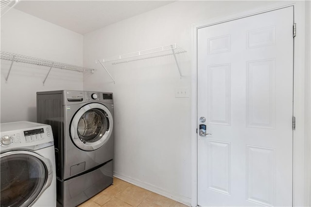 clothes washing area featuring washer and clothes dryer and light tile patterned floors