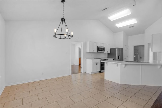 kitchen with stainless steel appliances, pendant lighting, a chandelier, white cabinetry, and high vaulted ceiling