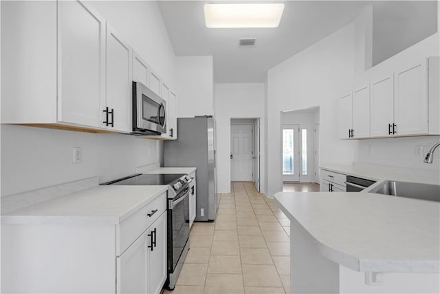 kitchen featuring kitchen peninsula, stainless steel appliances, sink, light tile patterned floors, and white cabinets