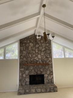 unfurnished living room with a fireplace, a chandelier, lofted ceiling with beams, and a wealth of natural light