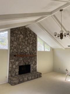 unfurnished living room featuring a stone fireplace, a healthy amount of sunlight, and vaulted ceiling with beams