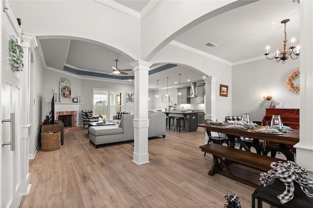 living room with ornate columns, visible vents, and ceiling fan with notable chandelier