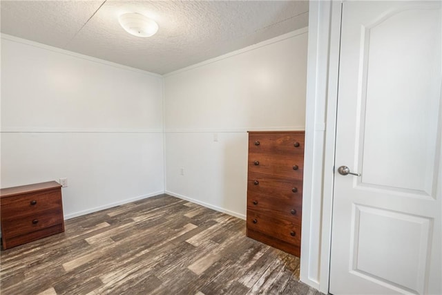 unfurnished room featuring dark wood-type flooring and a textured ceiling