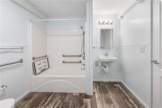 bathroom with hardwood / wood-style flooring, shower / tub combination, and toilet