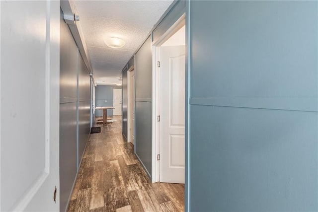 corridor featuring dark wood-type flooring and a textured ceiling