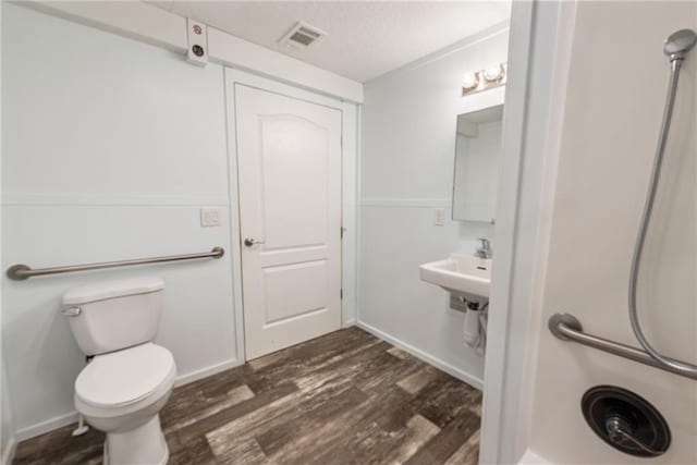 bathroom with hardwood / wood-style floors, toilet, and a textured ceiling