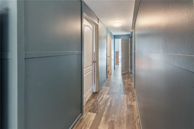 hall with dark wood-type flooring and a textured ceiling