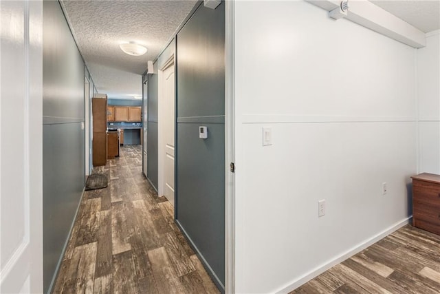 hallway with dark hardwood / wood-style floors and a textured ceiling