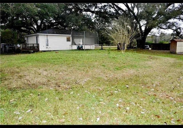 view of yard featuring a trampoline and a wooden deck