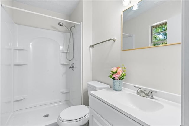 bathroom featuring walk in shower, a textured ceiling, toilet, and vanity