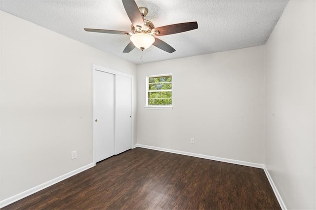 unfurnished bedroom with baseboards, dark wood-style flooring, a textured ceiling, and a closet