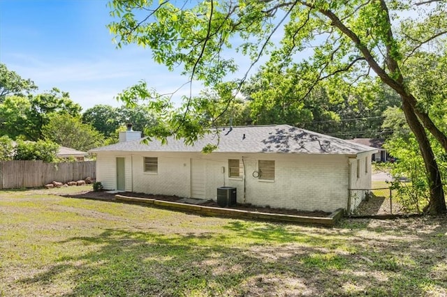 rear view of property featuring brick siding, a lawn, a chimney, and fence