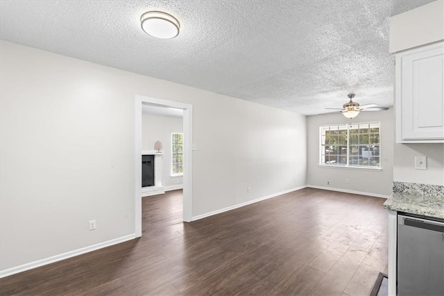 unfurnished living room featuring a textured ceiling, a ceiling fan, baseboards, and dark wood-style flooring