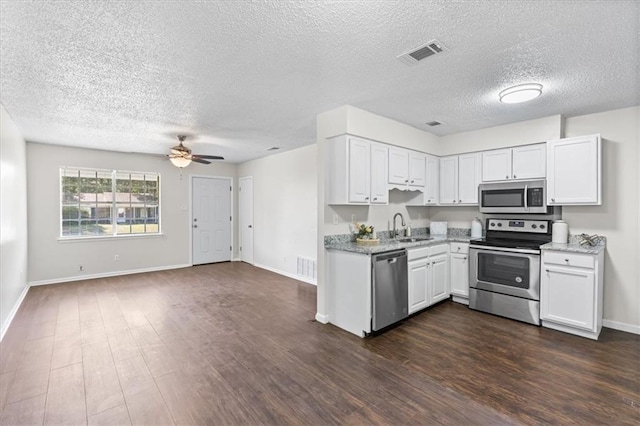 kitchen featuring dark wood finished floors, visible vents, a sink, a textured ceiling, and appliances with stainless steel finishes