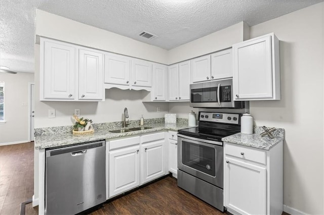 kitchen with appliances with stainless steel finishes, a sink, a textured ceiling, and visible vents