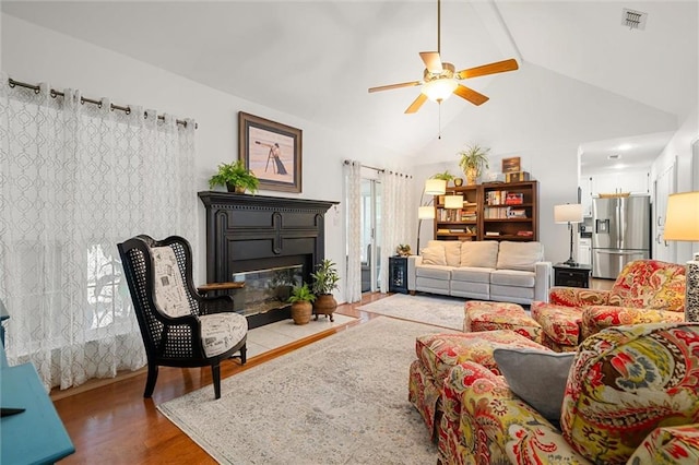 living room featuring hardwood / wood-style flooring, ceiling fan, beam ceiling, and high vaulted ceiling