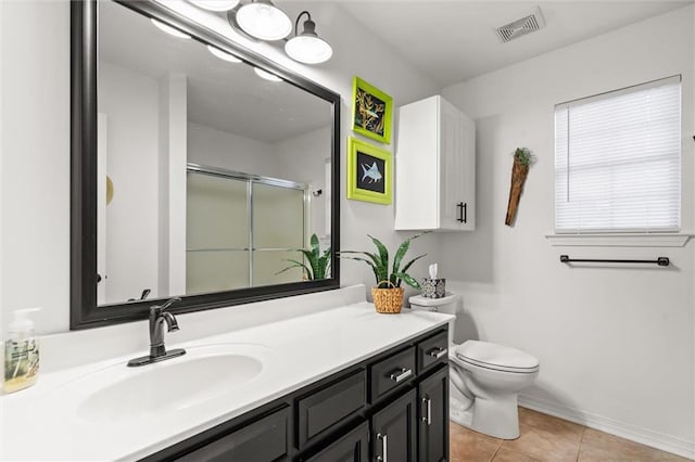 bathroom featuring tile patterned floors, vanity, toilet, and a shower with shower door