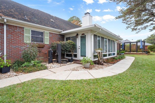 exterior space featuring a front yard, a wooden deck, and a sunroom