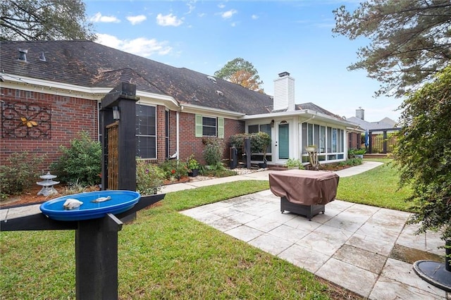 rear view of house with a sunroom, a yard, and a patio