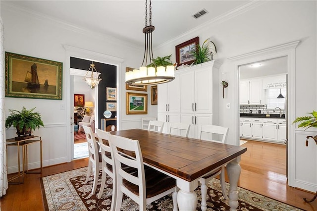 dining area with light hardwood / wood-style flooring, ornamental molding, and sink