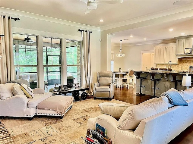 living room with ceiling fan, ornamental molding, and sink