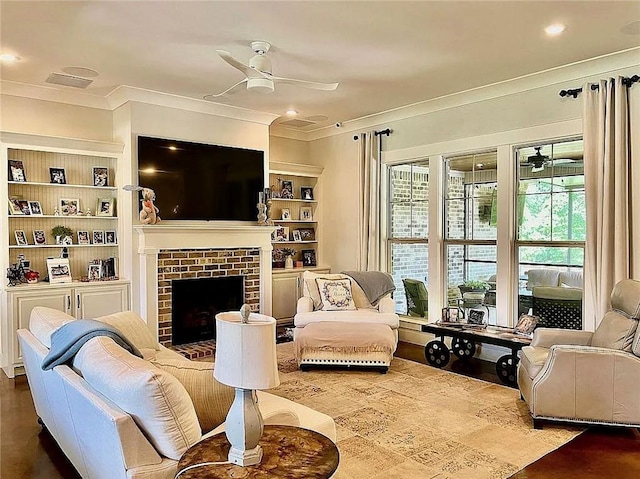 living room featuring built in features, a brick fireplace, ceiling fan, and crown molding