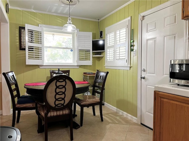 dining space featuring crown molding, plenty of natural light, light tile patterned flooring, and wooden walls