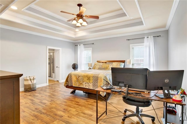 bedroom with light wood-type flooring, a raised ceiling, multiple windows, and crown molding